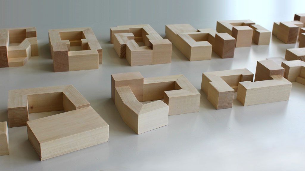 Einzelne Baukörper aus Lindenholz auf einem weißen Tisch von schräg oben fotografiert