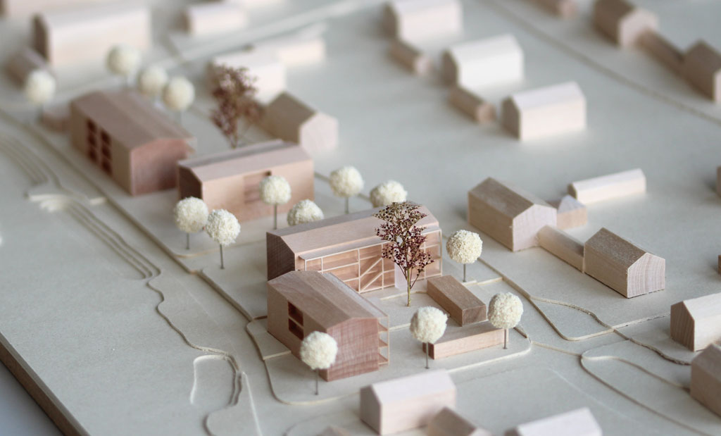 Architekturmodell mit Gebäuden aus Holz, Höhenschichten aus Finnpappe. Die Umgebungsgebäude sind vereinfacht dargestellt, die neue Planung detaillierter mit vorgestellten Laubengängen, Aufzügen und eingefrästen Loggien. Im Bereich des überplanten Gebietes sind Bäume aus Schwammgummikugeln und getrocknetem Seemoos gesetzt.