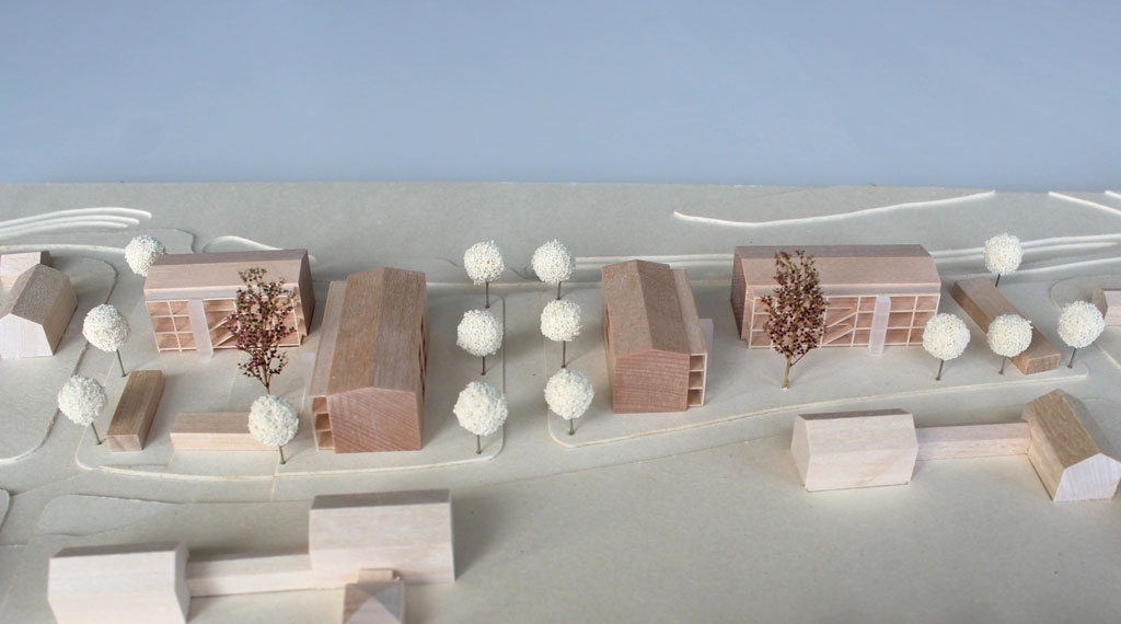 Architekturmodell mit Gebäuden aus Holz, Höhenschichten aus Finnpappe. Die Umgebungsgebäude sind vereinfacht dargestellt, die neue Planung detaillierter mit vorgestellten Laubengängen, Aufzügen und eingefrästen Loggien. Im Bereich des überplanten Gebietes sind Bäume aus Schwammgummikugeln und getrocknetem Seemoos gesetzt.