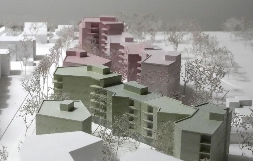 Das Foto zeigt ein Architekturmodell mit weißer Umgebung. Die neugeplanten Baukörper sind mehrgeschossige Volumina mit auskragenden Balkonen und verschiedenen Grün- und Rosatönen