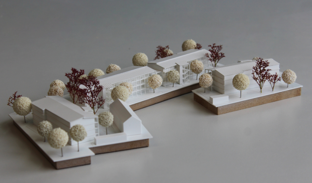 weißes Architekturmodell auf zwei Einsatzplatten mit insgesamt fünf Wohngebäuden.