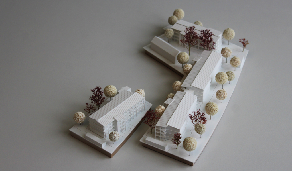 weißes Architekturmodell auf zwei Einsatzplatten mit insgesamt fünf Wohngebäuden.