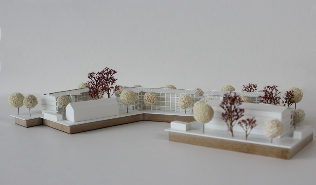 weißes Architekturmodell auf zwei Einsatzplatten mit insgesamt fünf Wohngebäuden.