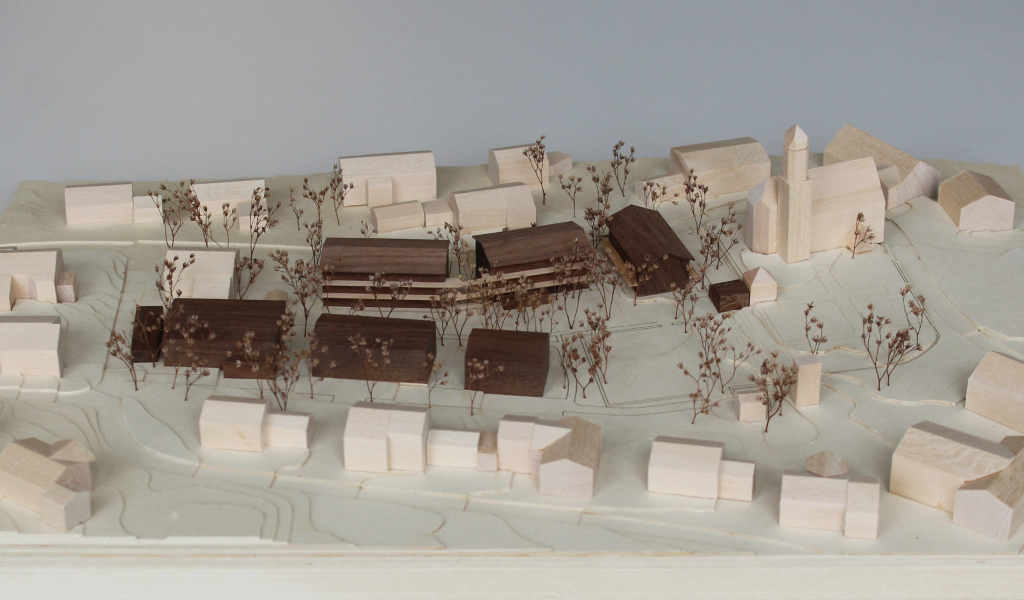 Architekturmodell mit Höhenschichten aus gelblicher Finnpappe, Gebäuden aus Linden- und Nussbaumholz. Die neu geplanten Wohngebäude sind aus Nussbaumholz mit eingefrästen Loggien. Die Balkonflächen sind aus hellem Birkenholz. v