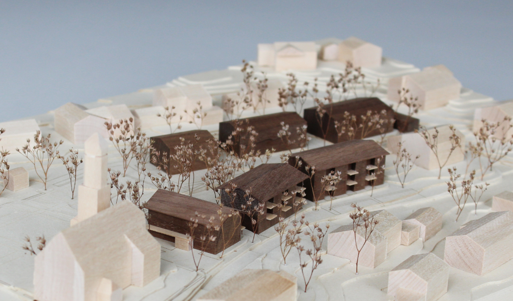 Architekturmodell mit Höhenschichten aus gelblicher Finnpappe, Gebäuden aus Linden- und Nussbaumholz. Die neu geplanten Wohngebäude sind aus Nussbaumholz mit eingefrästen Loggien. Die Balkonflächen sind aus hellem Birkenholz.