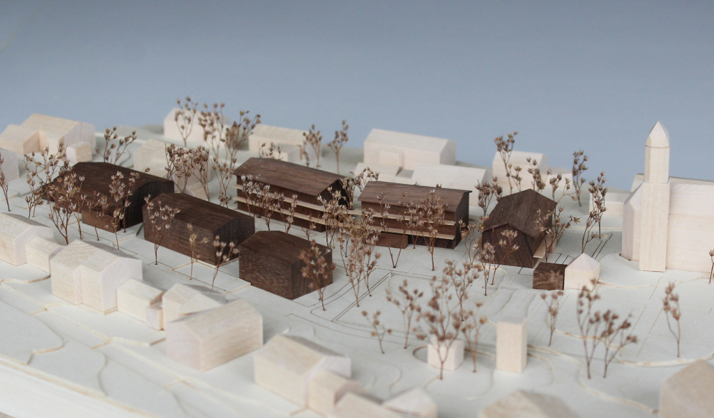 Architekturmodell mit Höhenschichten aus gelblicher Finnpappe, Gebäuden aus Linden- und Nussbaumholz. Die neu geplanten Wohngebäude sind aus Nussbaumholz mit eingefrästen Loggien. Die Balkonflächen sind aus hellem Birkenholz.