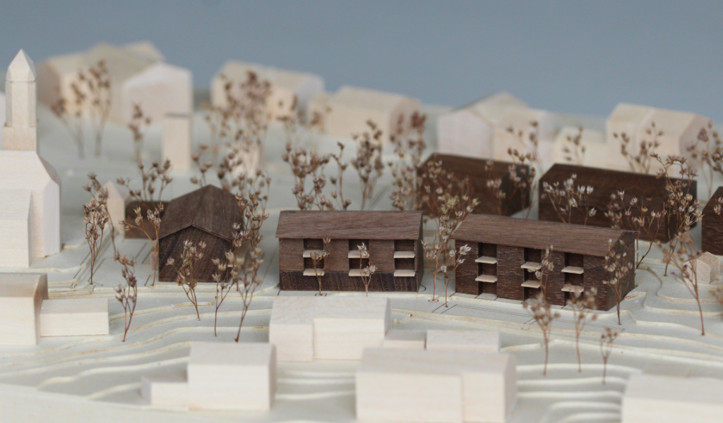 Architekturmodell mit Höhenschichten aus gelblicher Finnpappe, Gebäuden aus Linden- und Nussbaumholz. Die neu geplanten Wohngebäude sind aus Nussbaumholz mit eingefrästen Loggien. Die Balkonflächen sind aus hellem Birkenholz.