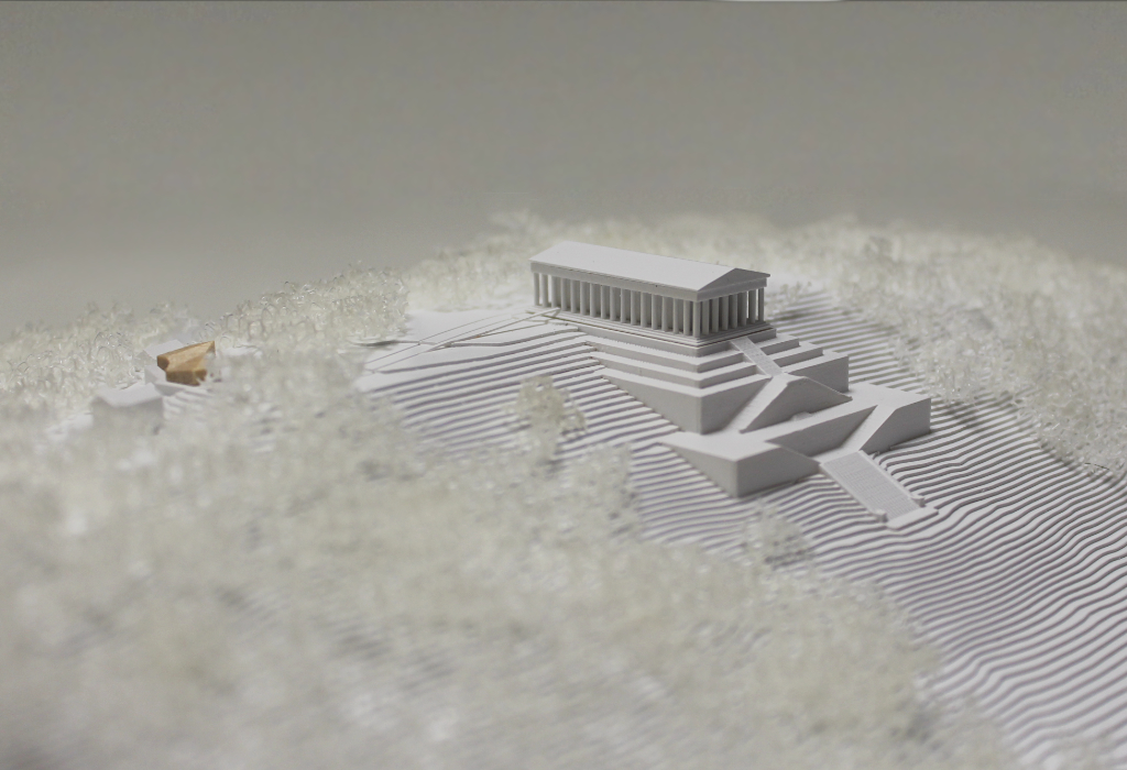 weißes Architekturmodell von der Walhalla und Umgebung. Der Höhenverlauf ist mittels Höhenschichten dargestellt, zur Dargestellung der Bäume ist weißer Pflanzenschaum flächig verklebt. Der Neubau des Besucherzentrums liegt nordöstlich von der Walhalla und besteht aus einem weißen Sockel auf dem ein kleines Holzvolumen mit mehreren Dachverschneidungen sitzt. Ansicht von Südost.